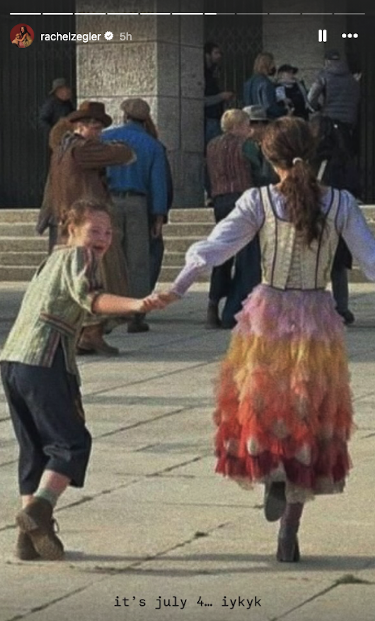 Rachel Zegler skipping away as Lucy Gray Baird in Hunger Games: Ballad of Songbirds and Snakes with caption "it's july 4... iykyk"