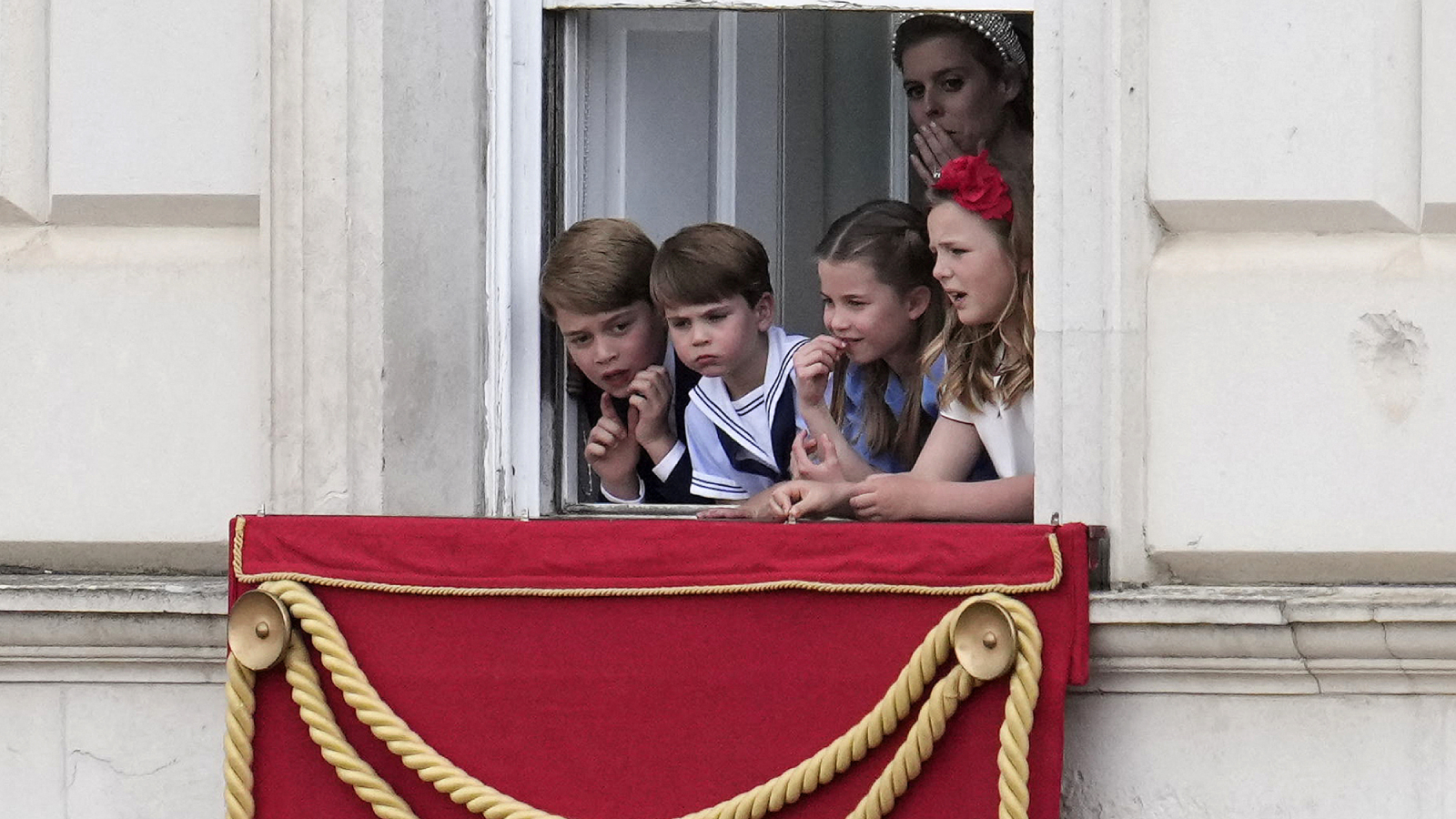 Princezna Beatrice z Yorku stojí s britským princem Georgem z Cambridge, britskou princeznou Charlotte z Cambridge (2R) a britským princem Louisem z Cambridge na hlídkách s výhledem na Horse Guards, zatímco vojáci pochodují kolem během průvodu královniných narozenin.