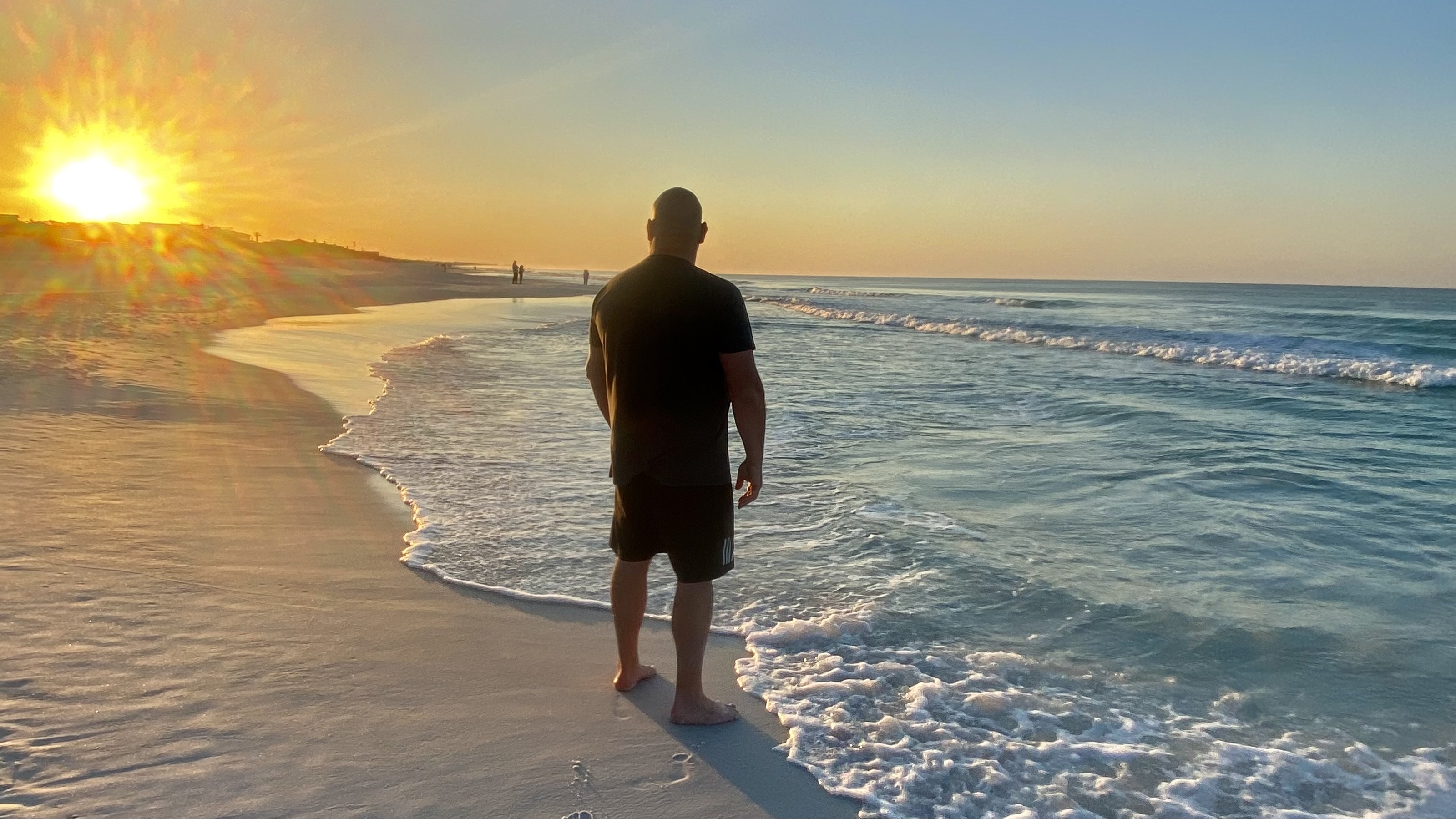 A man watching the sunset at the beach.