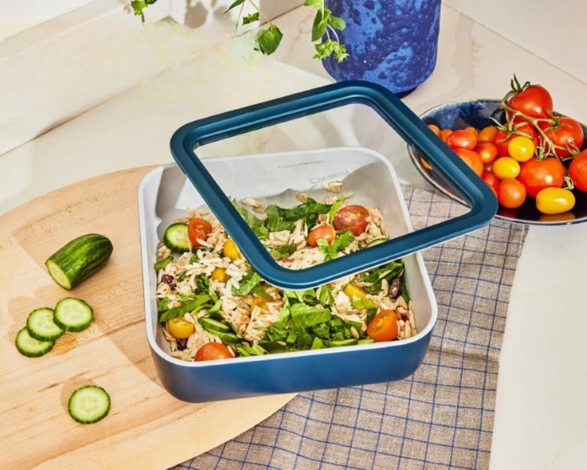 Navy Caraway food storage on a table with a plate of tomatoes nearby
