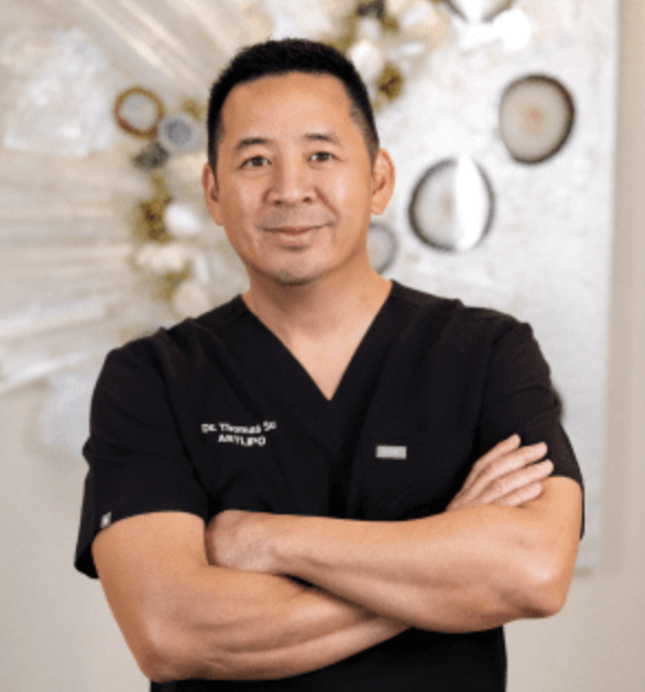 an asian man in black scrubs with his arms crossed
