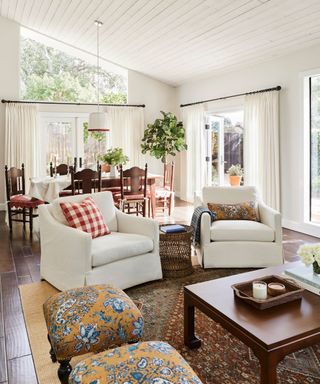 living room with white armchairs and checked cushions with view of dining room