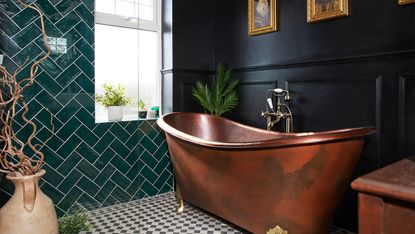 Black bathroom with copper bath and monochrome floor tiles
