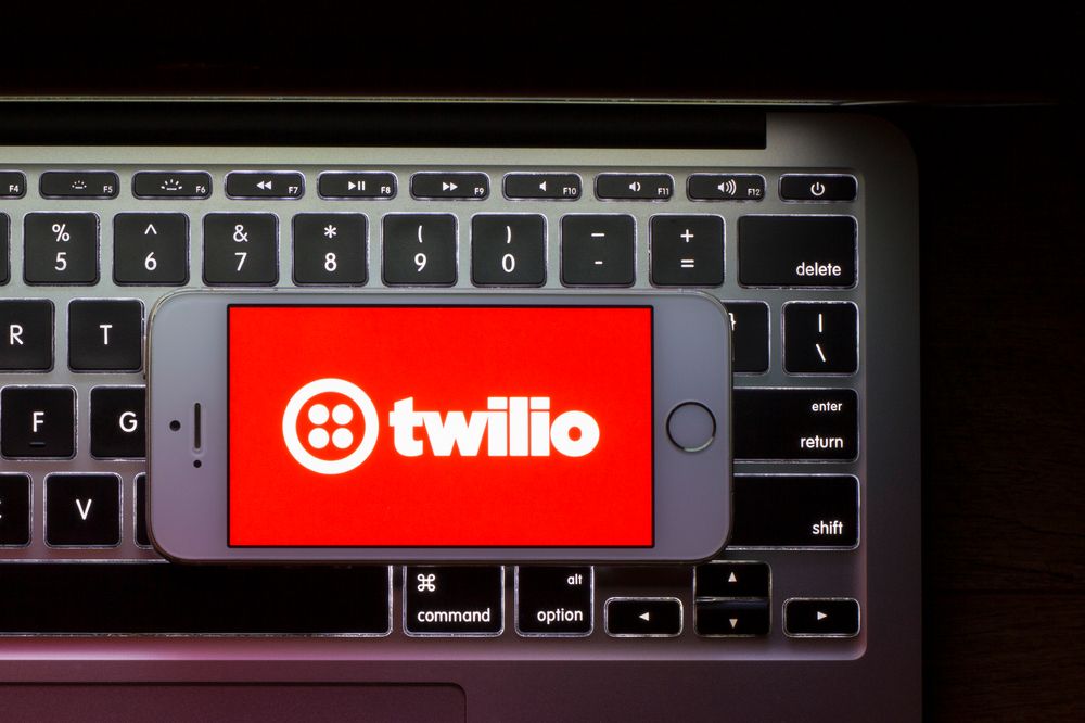 The red Twilio logo on an iPhone screen that&amp;#039;s sat on top of a MacBook keyboard