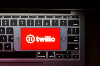 The red Twilio logo on an iPhone screen that's sat on top of a MacBook keyboard