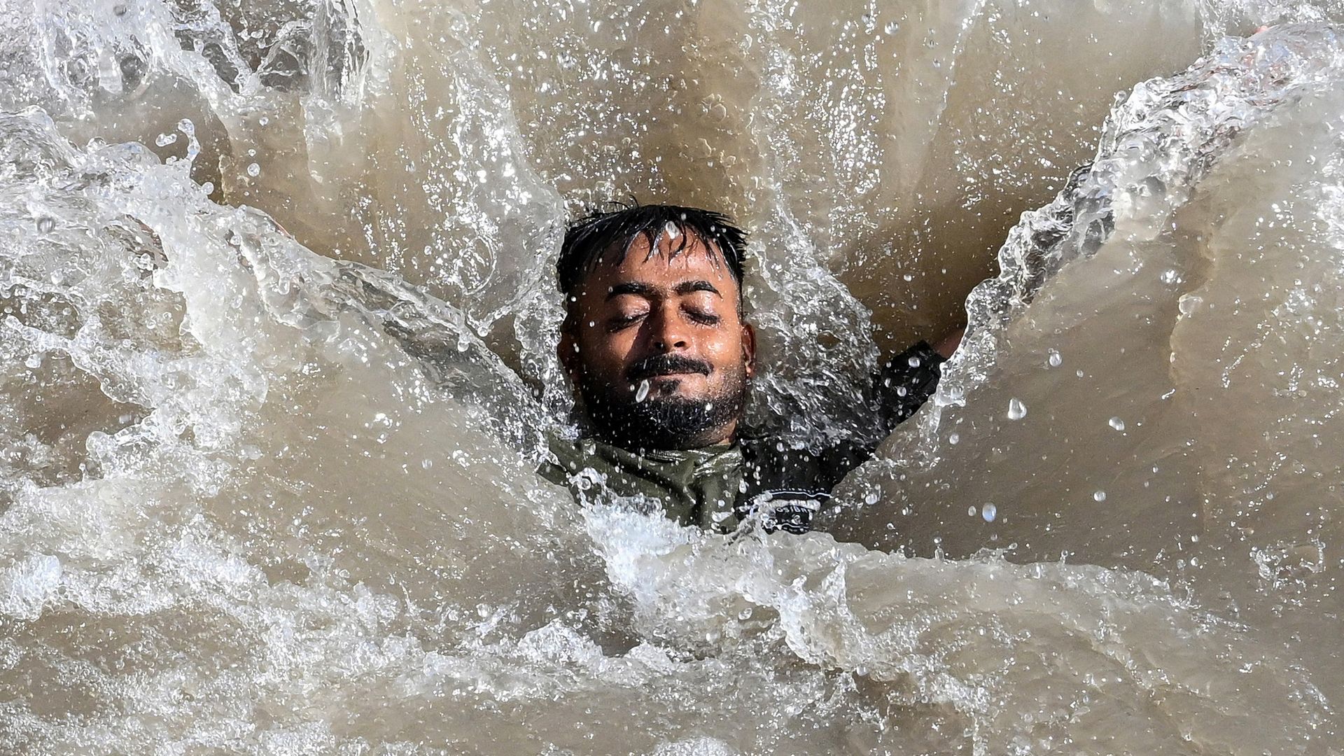 
                                A man swims in a canal to cool off on a hot summer afternoon in Lahore, Pakistan
                            
