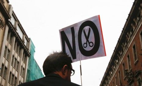 A man holds a banner at a protest against Spain&amp;#039;s 2013 budget cuts in front of the Economy Ministry in Madrid on Sept. 28.