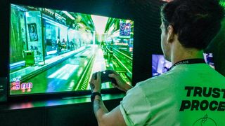 Person playing game on display holding controller