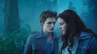 A still from the movie Twilight in which Edward and Bella are in a dark forest with a lot of blue lighting. They look worried and pensive.
