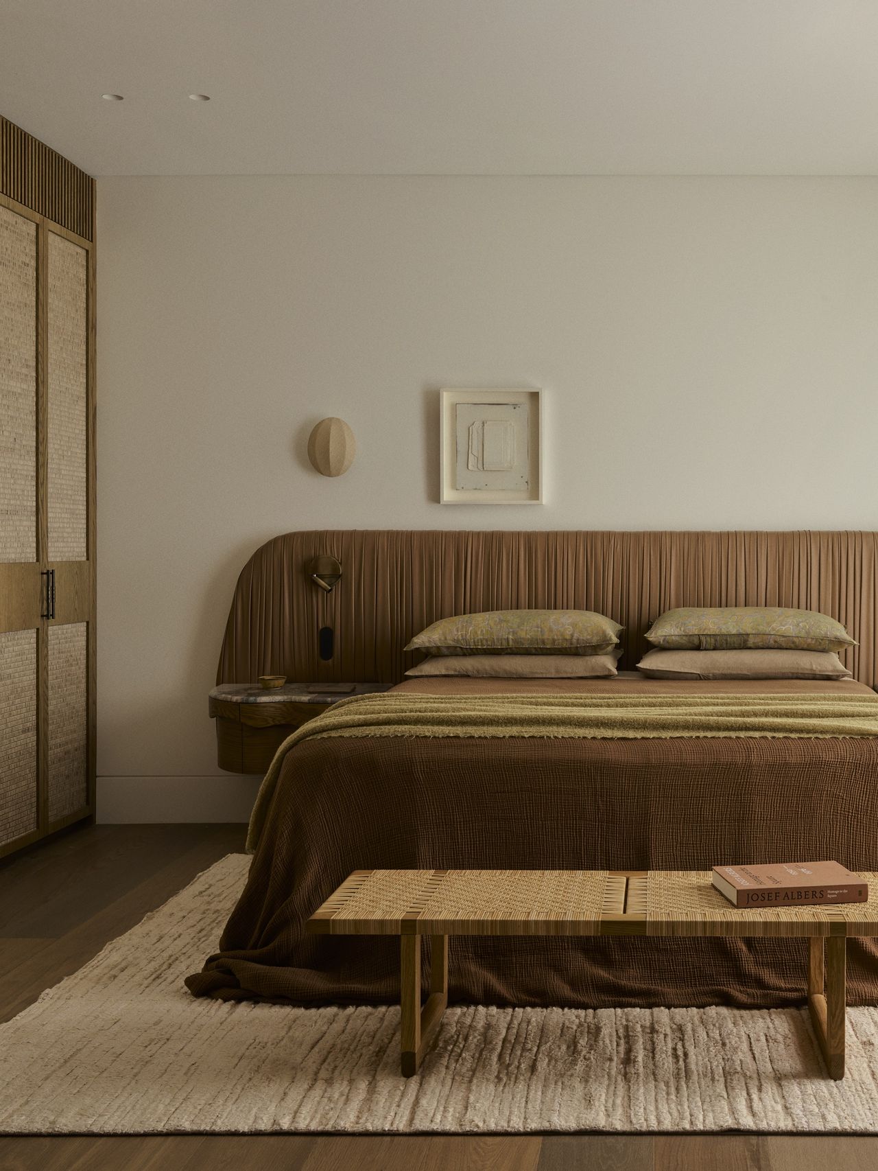 a bedroom with a leather headboard and neutral beddings