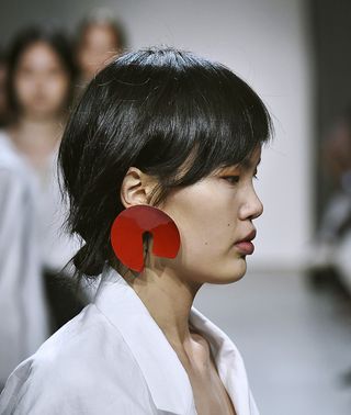 Model wearing white dress and red earring