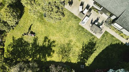 An aerial view of a man mowing the grass in his backyard