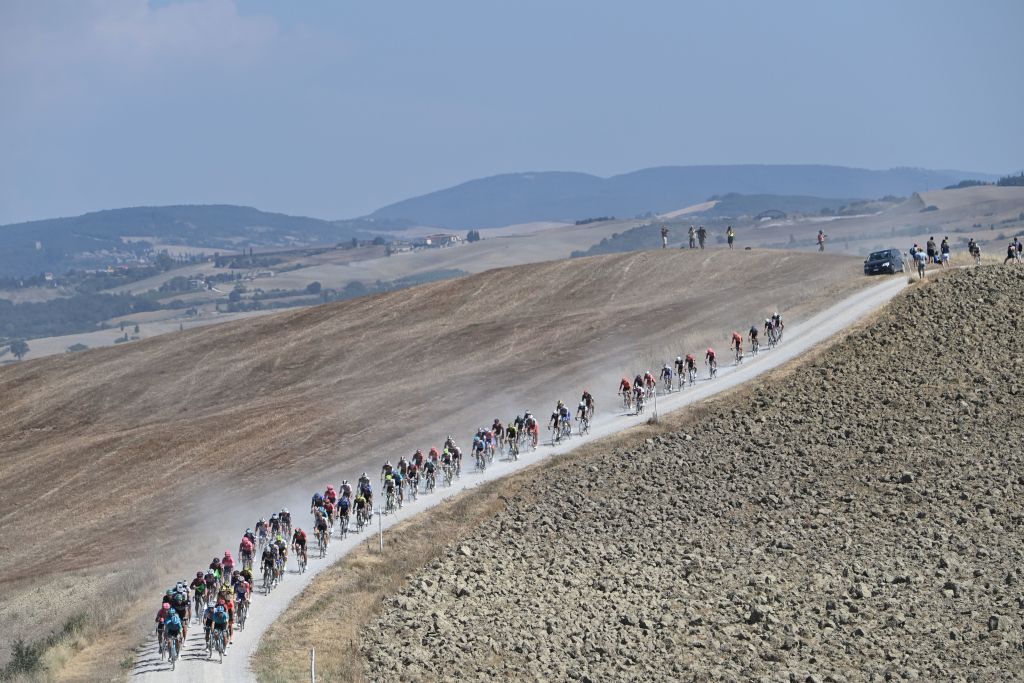 The pack of riders pedal through a dusty gravel road during the oneday classic cycling race Strade Bianche White Roads on August 1 2020 in Siena Tuscany Photo by Marco BERTORELLO AFP Photo by MARCO BERTORELLOAFP via Getty Images