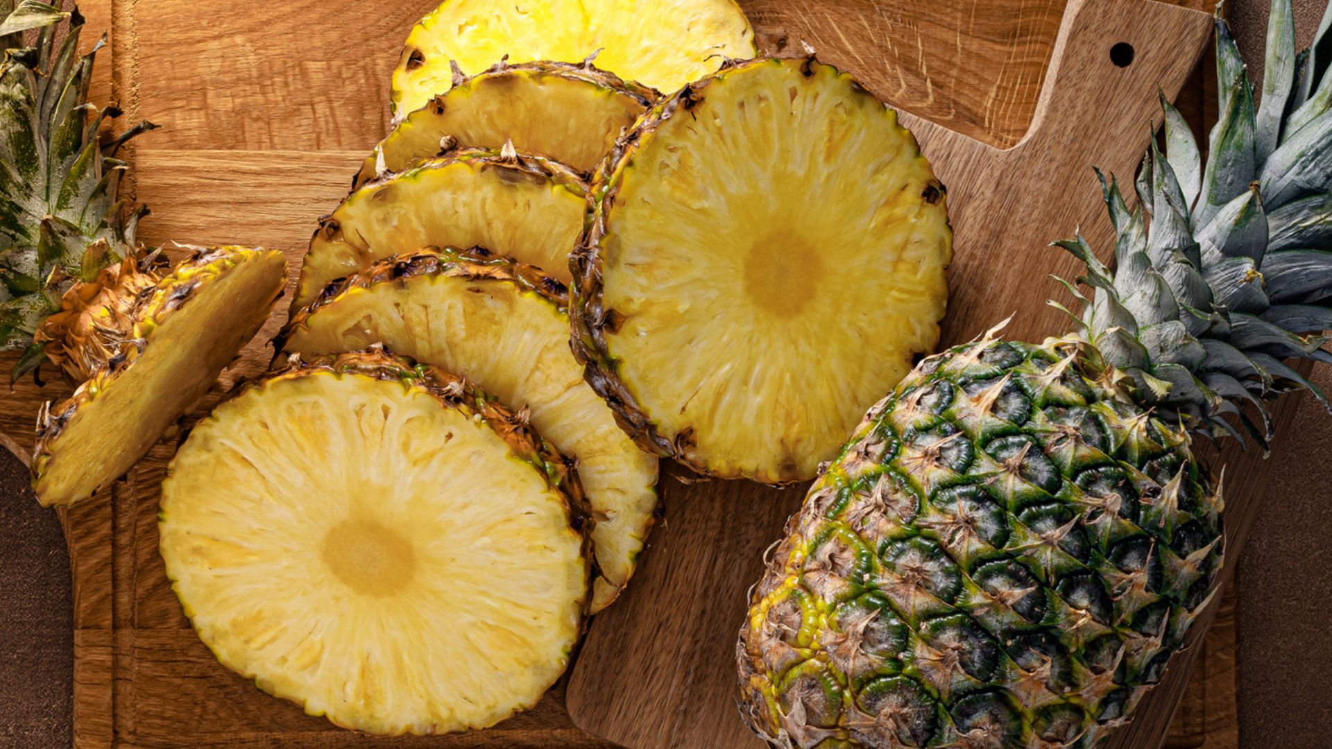 Chopped and whole pinapple sitting on wooden chopping board