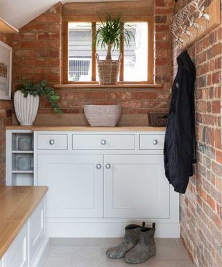 mudroom with exposed brick and white cabinets