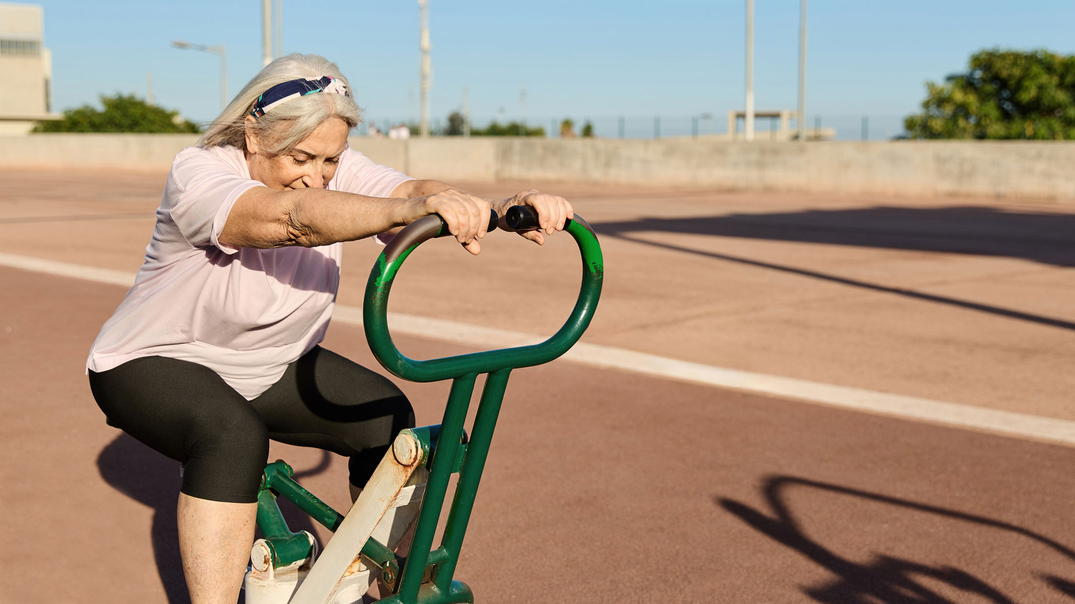 A woman exercising on a hydraulic rowing machine in an outdoor gym