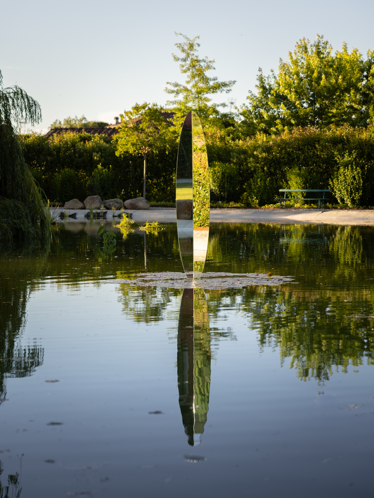 a mirrored sculpture emerging from a lake