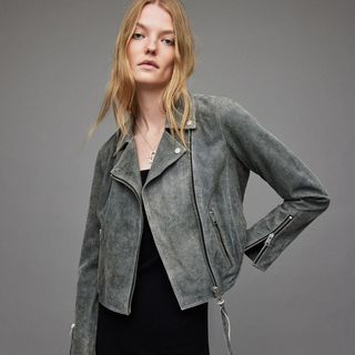 model against a grey background wearing a grey suede leather jacket from allsaints