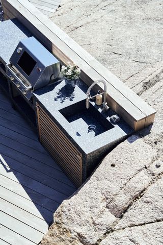 an outdoor kitchen with stone countertops and a sink