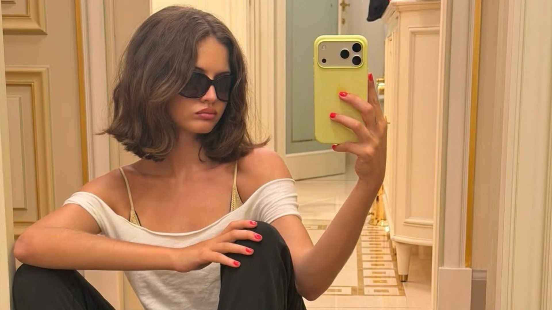 Influencer @rubylyn_ takes a mirror selfie wearing black trousers with leopard print Vans Authentic trainers and a white off-the-shoulder top.
