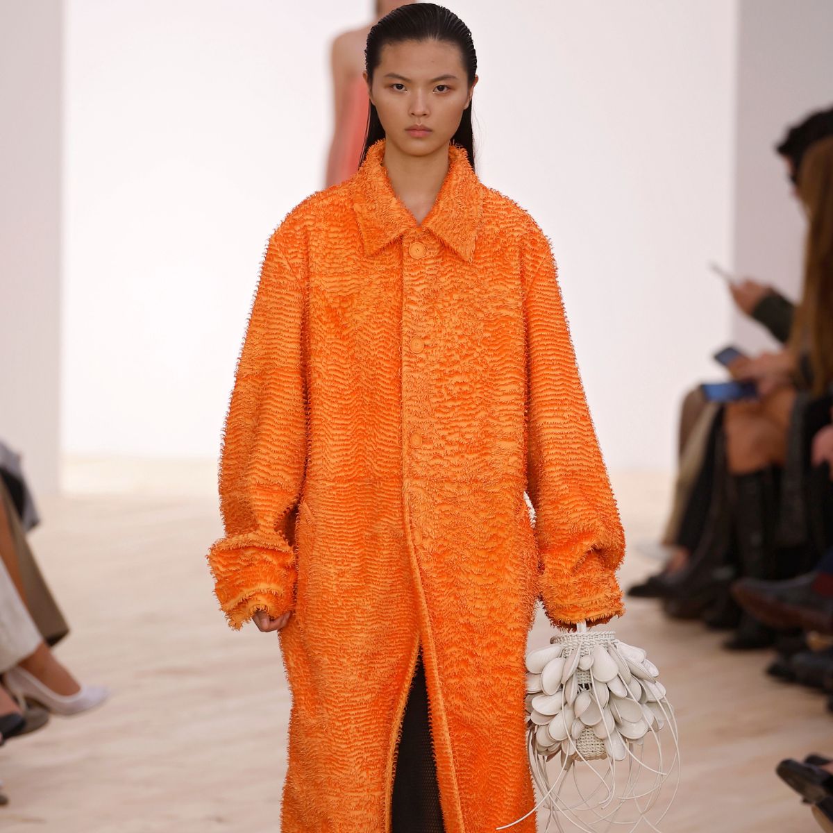 a model at loewe ss26 wearing an orange coat