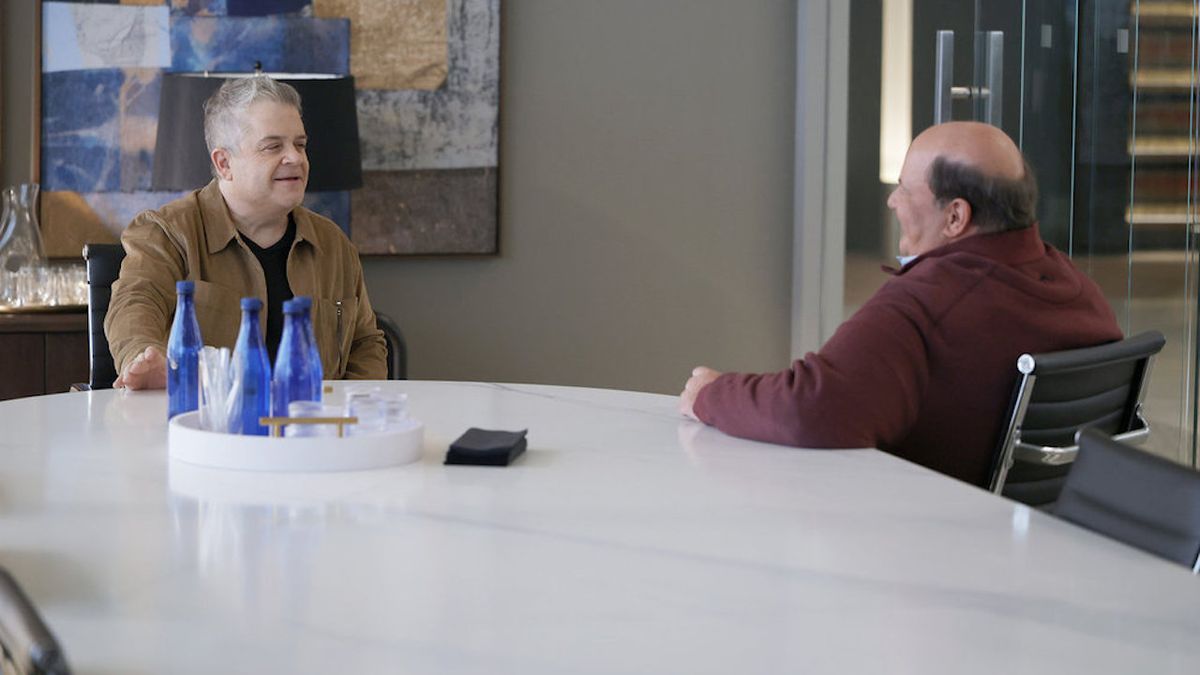 Patton Oswalt and Brian Baumgartner speaking to each other at conference table in Suits LA