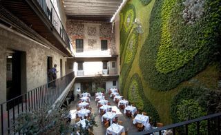 Restaurant and floor balcony's overshadowed by large wall of grass and flowerbeds
