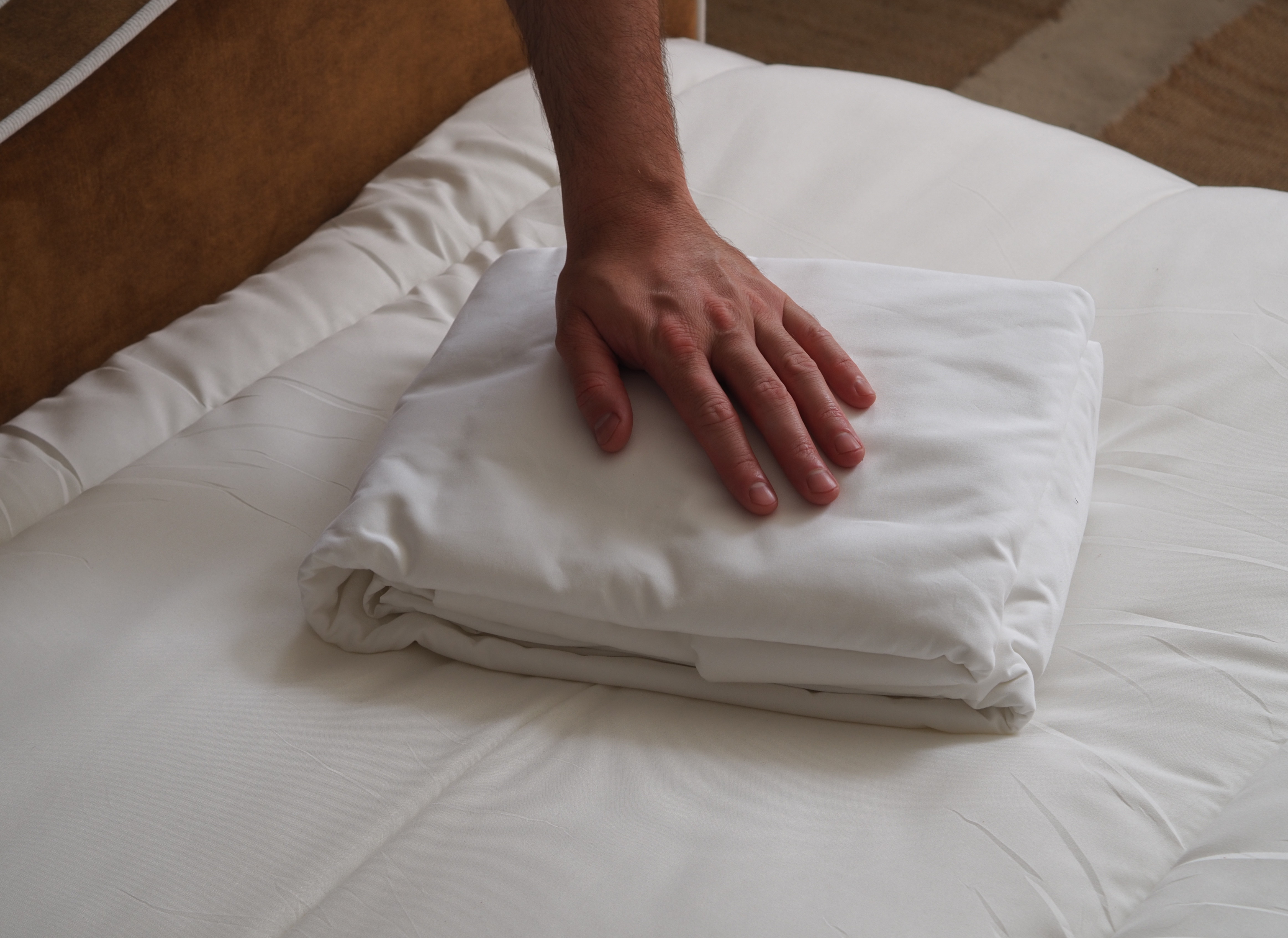 rise and fall bedding on a bed being touched by a hand