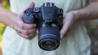 Two hands holding the Nikon D3500 DSLR