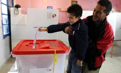 A Tunisian man holds his son as he casts a vote at a polling station