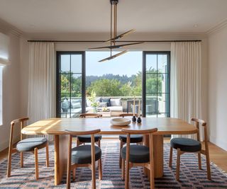 Modern dining room with large wooden table and doors opening onto a patio