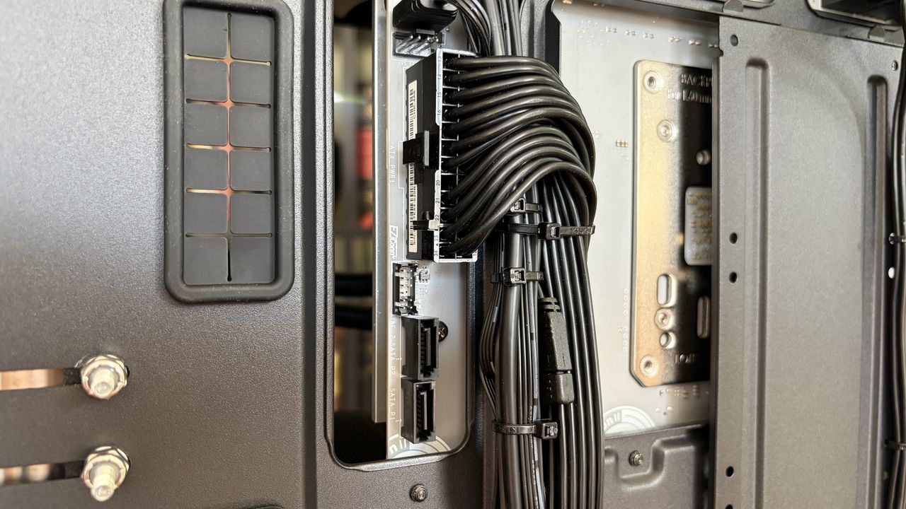 Close-up of a sleek MG-1 MK.II computer case interior showcasing organized black cables connected to a hub. The tone is technical and tidy, emphasizing precision.
