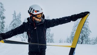 A backcountry skier pulls the skins off his skis for the descent