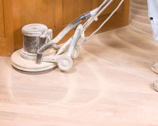 A wood floor being refinished using a sander