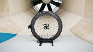 A front Vision Metron wheel sits in front of the fan within a wind tunnel