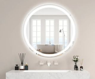 round mirror with LED light on pink wall with marble vanity unit below