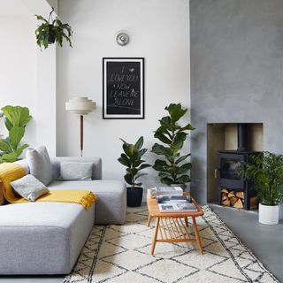 Modern white living room with concrete floors and feature wall, grey sofa and wood burner