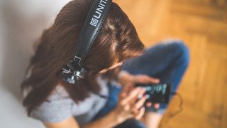 Photo of girl wearing headphones playing music on her phone