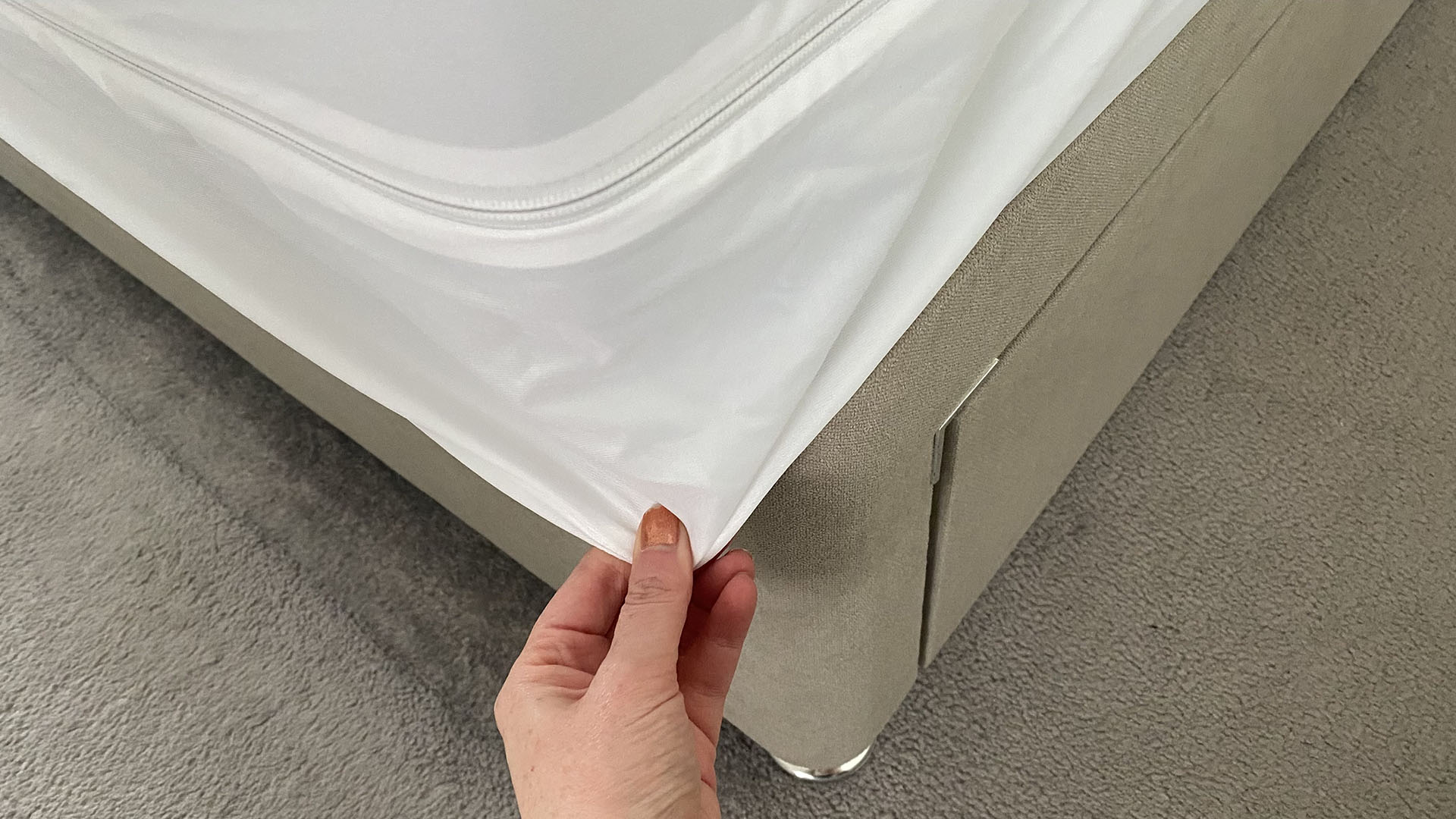 A close up of a hand holding the corner of the Linenspa Mattress Encasement away from the side of the mattress. There's clearly a lot of loose fabric