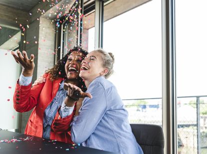 Two women throw confetti in the air as they celebrate Premium Bonds win.