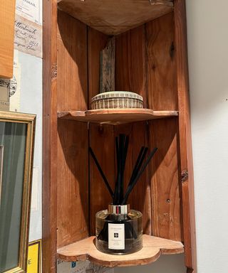 A Jo Malone diffuser with black reeds on an antique wooden shelf