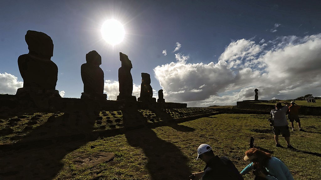 A group of tourists visit Moais (backgorund) -- stone statues of the Rapa Nui culture -- on Easter Island, 3700 km off the Chilean coast in the Pacific Ocean, on July 9, 2010