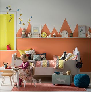 kids bedroom with multi colour painted wall and white table with chair