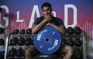 A photo of Marcus Rashford looking at the camera and leaning on a weight