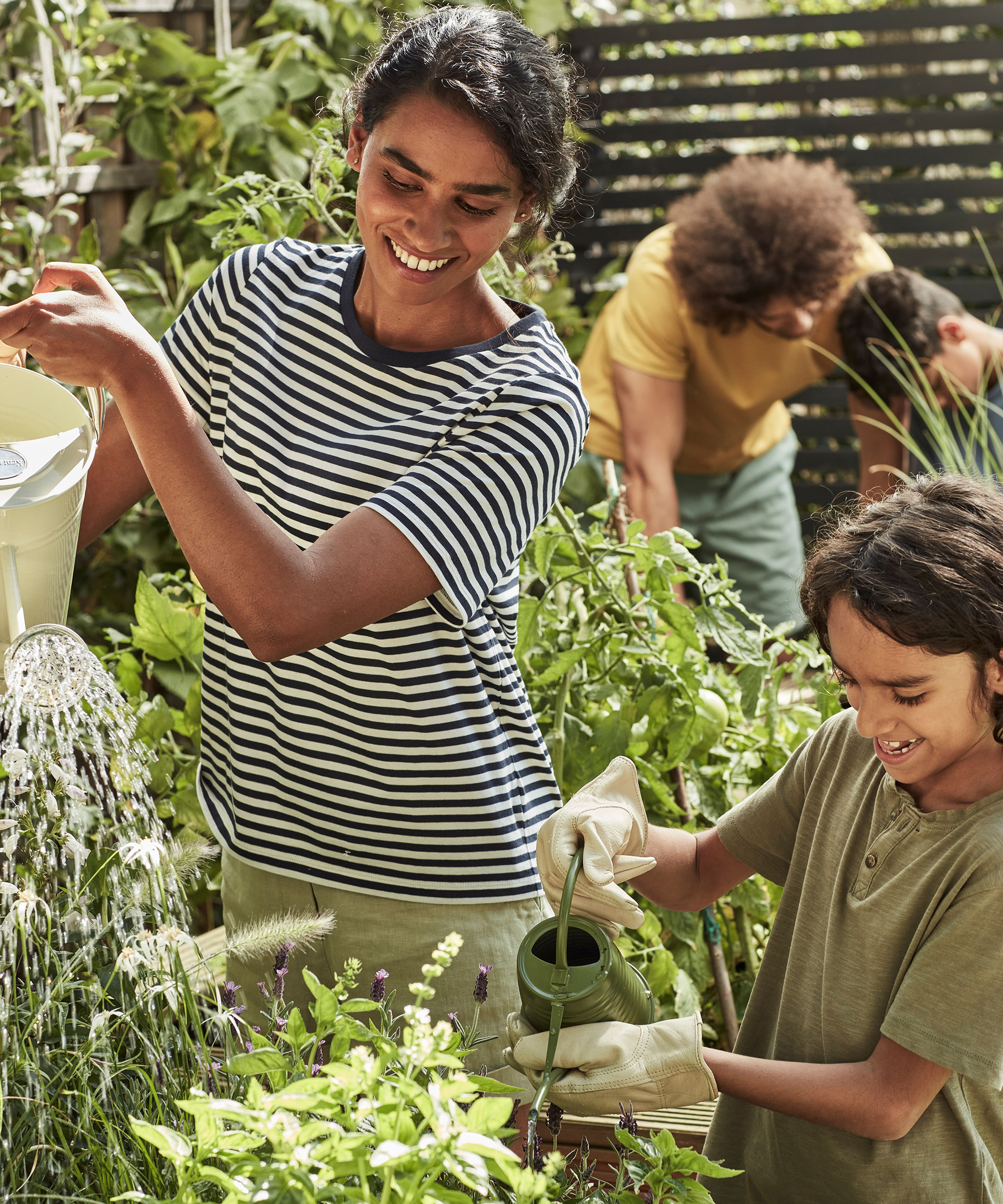 Family watering their garden on a sunny day