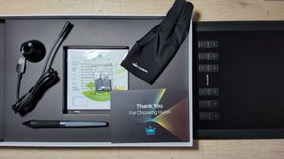 A photo fo the Huion Inspiroy H1060P tablet on a table for a review