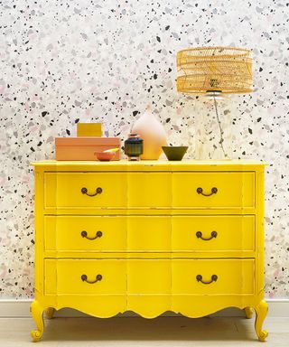 Light wallpaper and yellow cupboard in a living room