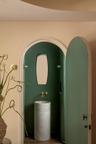 A small bathroom with beige outer walls and dark green interiors