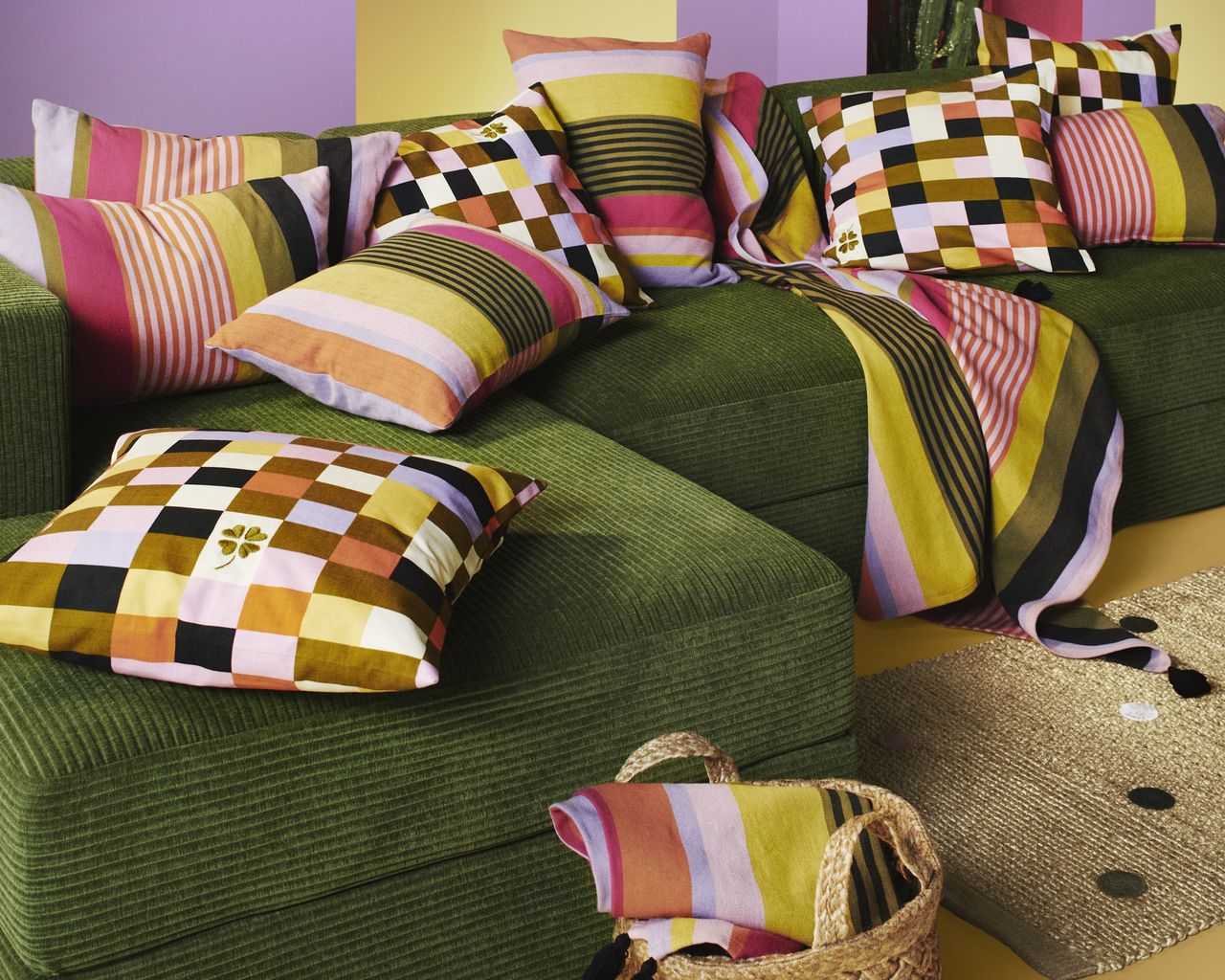 A green modular sofa with lots of colorful throw pillows