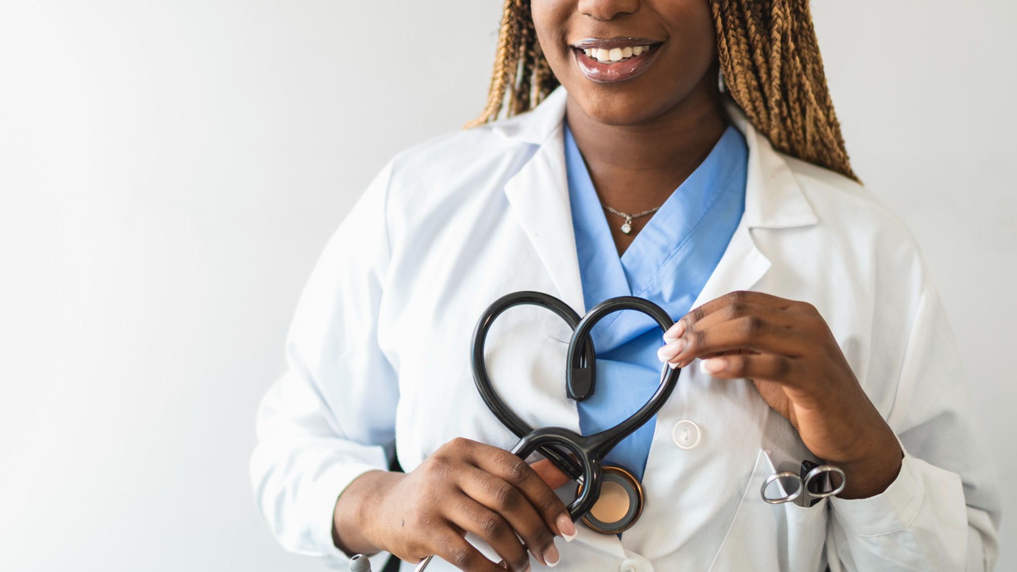 Smiling female medical doctor forming a heart shape with a stethoscope